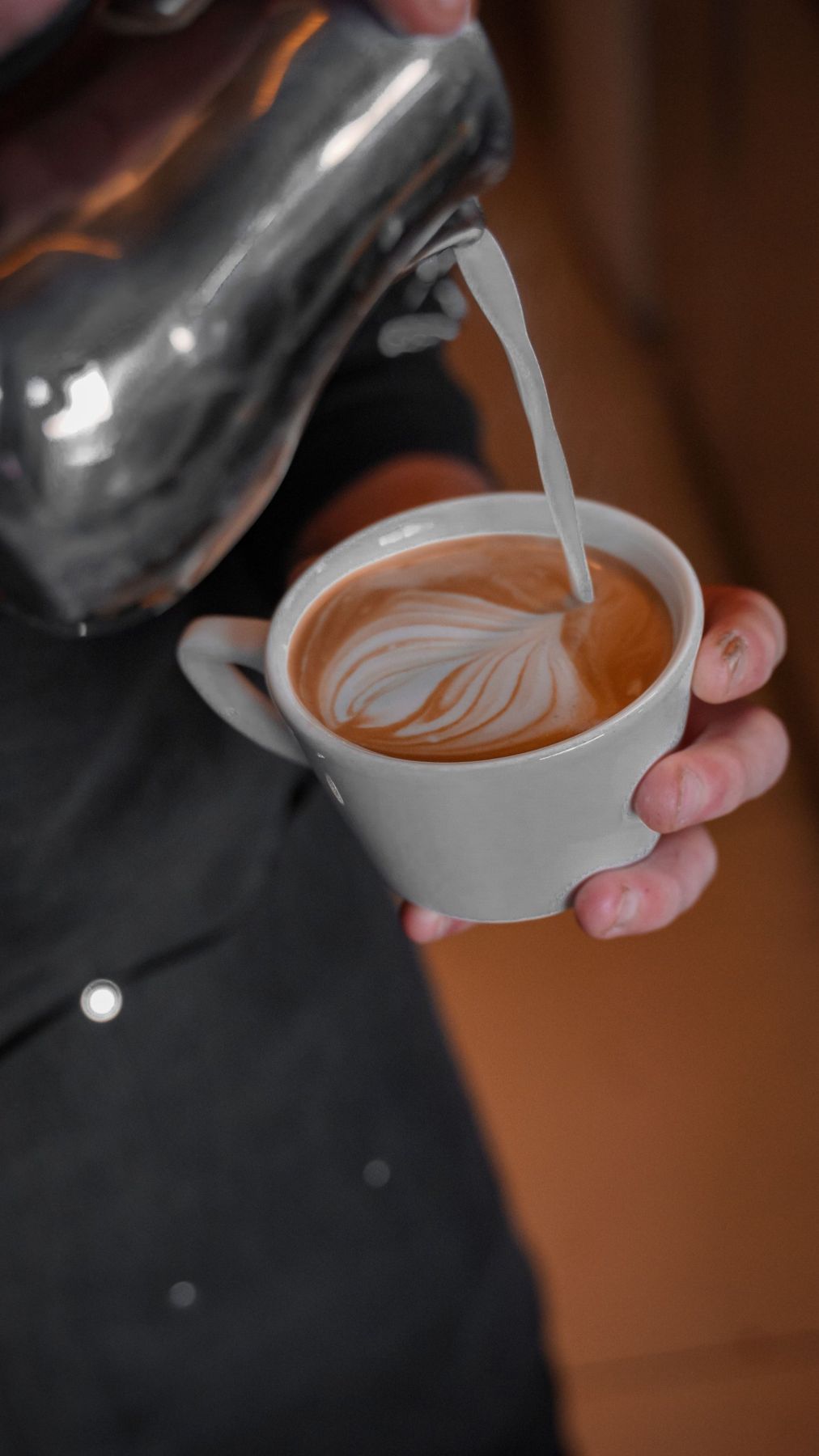 Milk being poured into a flat white